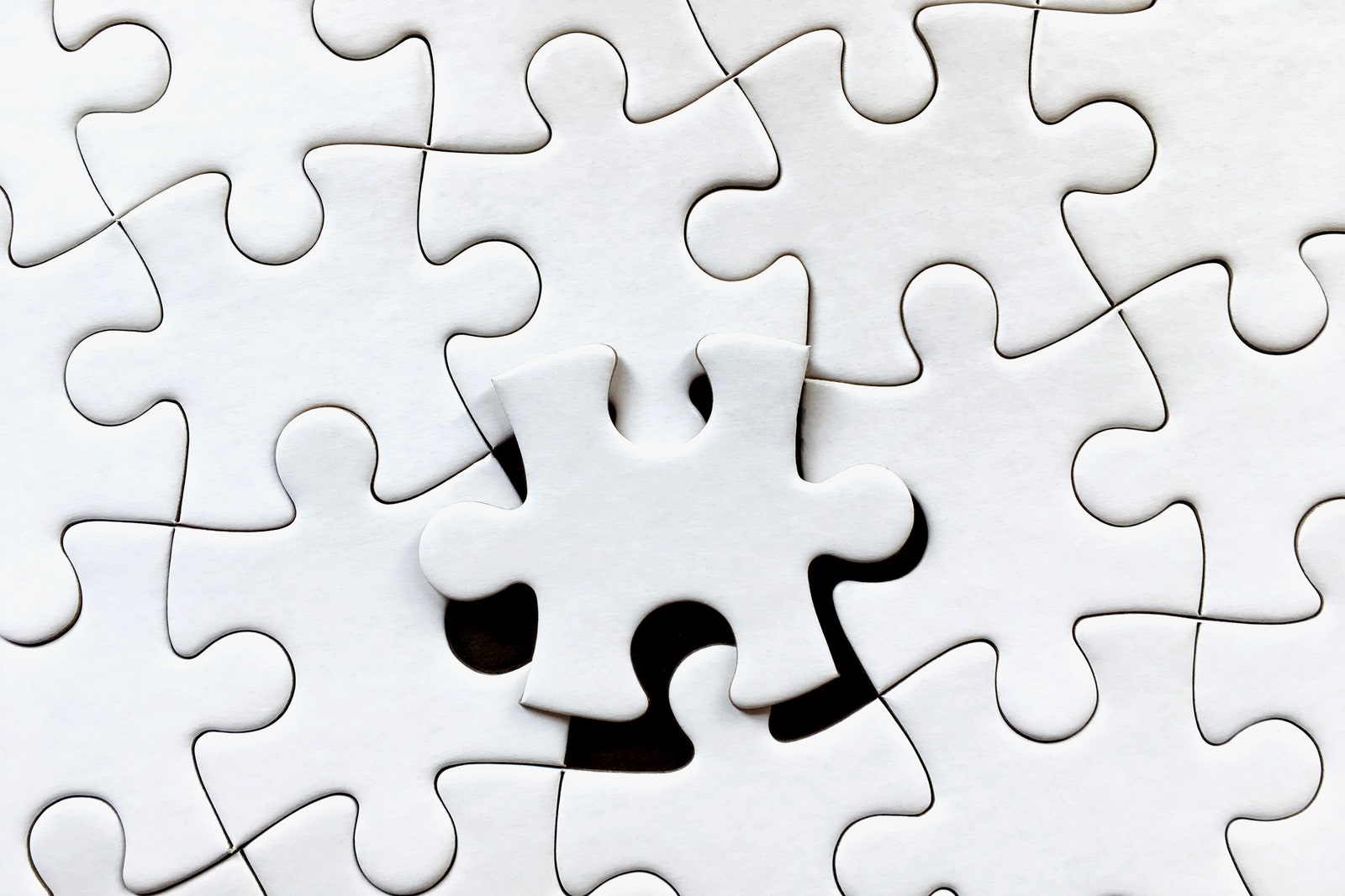 A nearly completed white jigsaw puzzle with one remaining piece laying on top web plugin concept